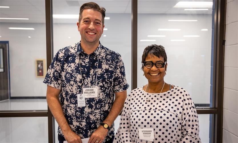 Two administrators stand together and smile